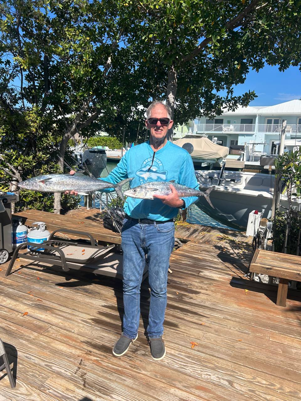 Ernie B holding two kingfish on a dock